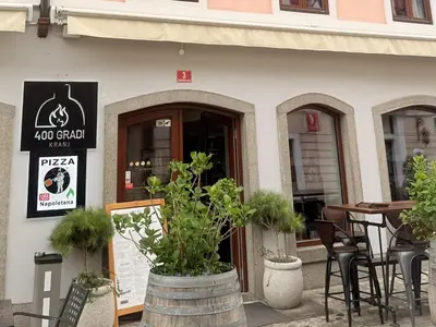 a restaurant with tables and chairs in front of a building at Apartments KrAnJ - City Studio Katka in Kranj