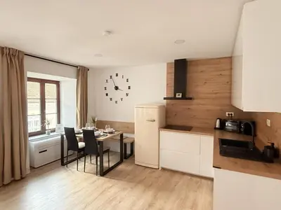 a kitchen with a table and chairs and a clock on the wall at Apartments KrAnJ - City Studio Katka in Kranj