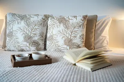 an open book on a bed with two cups and a tray at Apartma pod macesnom in Jesenice