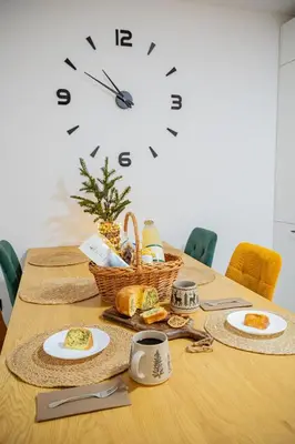 a table with plates of food and a clock on the wall at Apartma pod macesnom in Jesenice