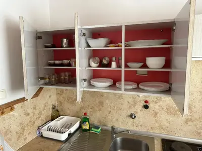 a kitchen with a sink and red shelves with dishes at Apartma Pri Kosu in Slovenska Bistrica