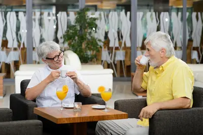 two older men sitting in chairs drinking orange juice at Hotel BIOTERME Mala Nedelja in Ljutomer