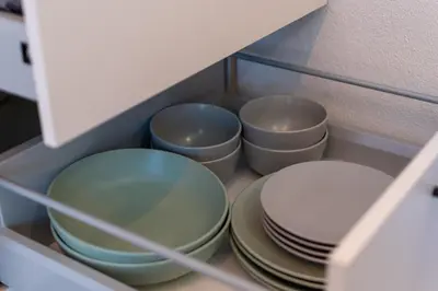 four bowls and plates in a drawer of a cabinet at Apartma Oleander in Kobarid