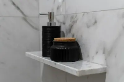 two black bottles sitting on a shelf in a bathroom at Apartma Oleander in Kobarid