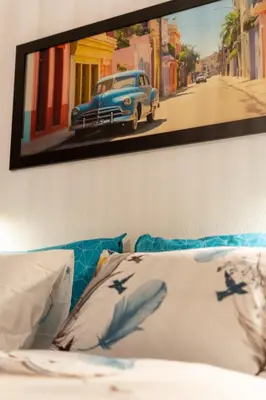 a painting of a car on a wall above a bed at Apartma Oleander in Kobarid