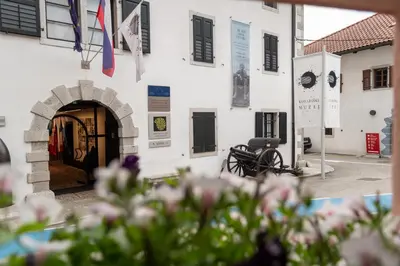 a white building with a door and flowers in the foreground at Apartma Oleander in Kobarid