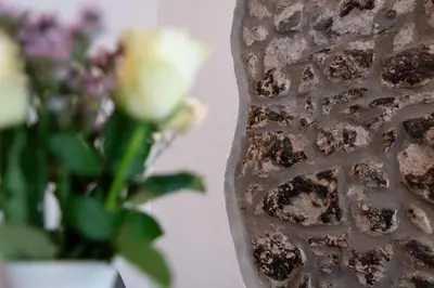 a vase with flowers in it next to a wall at Apartma Oleander in Kobarid