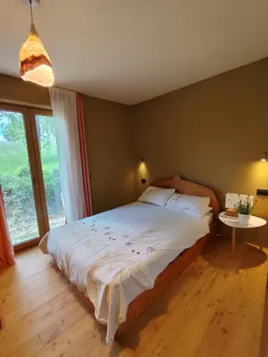 a bedroom with a large bed and a large window at Naravna lesena hiša v naravi z lastnim vrtom in Ig