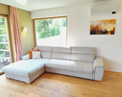 a living room with a white couch in front of a window at Naravna lesena hiša v naravi z lastnim vrtom in Ig