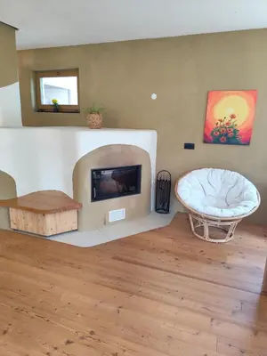 a living room with a fireplace and a chair at Naravna lesena hiša v naravi z lastnim vrtom in Ig