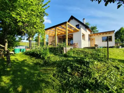 a house with a fence in the yard at Naravna lesena hiša v naravi z lastnim vrtom in Ig
