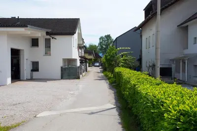 a street next to a white house and a hedge at Apartment Studio Green in Ljubljana
