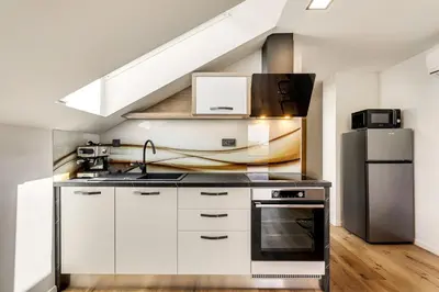 a kitchen with white cabinets and a stainless steel refrigerator at Apartmaji Kunej pod Gradom with sauna in Podsreda