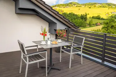 a patio with a table and chairs on a balcony at Apartmaji Kunej pod Gradom with sauna in Podsreda