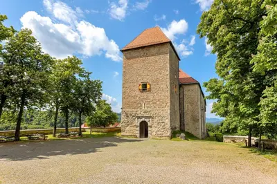 a building with a tower on a gravel road at Apartmaji Kunej pod Gradom with sauna in Podsreda
