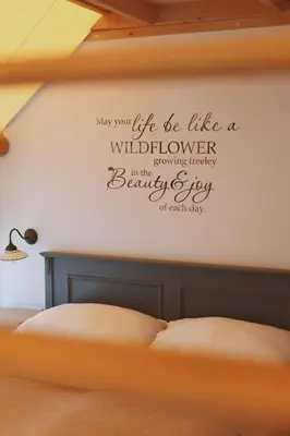 a bedroom with a bed with a quote on the wall at Herbal Glamping Resort Ljubno in Ljubno
