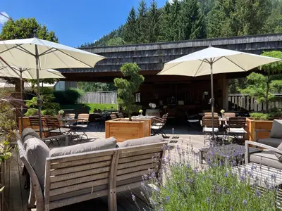 a patio with umbrellas and tables and chairs at Herbal Glamping Resort Ljubno in Ljubno