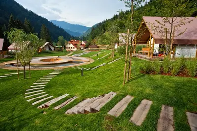 a park with a pathway in the grass with a building at Herbal Glamping Resort Ljubno in Ljubno