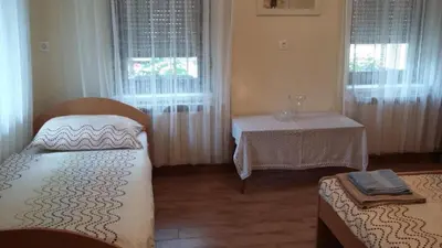 a room with two beds and a table and windows at Apartma Lovriž in Kobarid