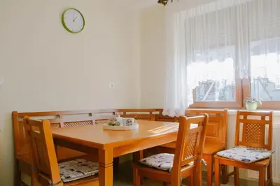 a dining room table and chairs with a clock on the wall at Apartma Lovriž in Kobarid