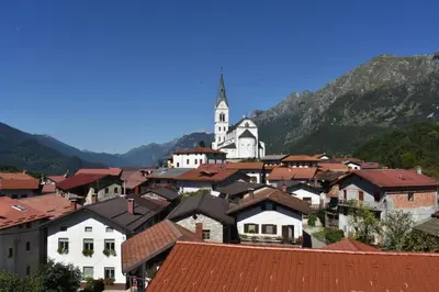 a small town with a church in the mountains at Apartma Lovriž in Kobarid