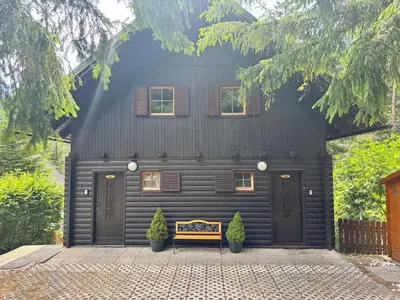 a black house with a bench in front of it at Hiša Jelka in Kranjska Gora
