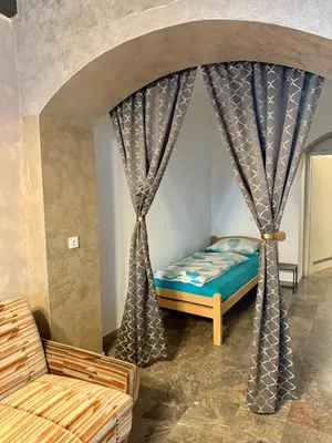 a bedroom with a bed and a couch and curtains at Historic studio apartment beneath the Ljubljana castle in the old city centre in Ljubljana