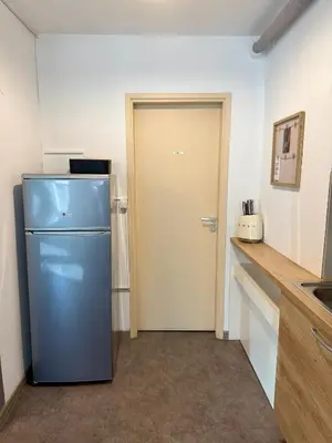 a kitchen with a blue refrigerator in a room at Historic studio apartment beneath the Ljubljana castle in the old city centre in Ljubljana