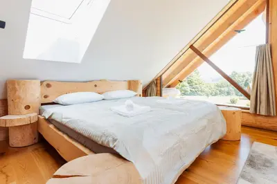 a bed in a room with a large window at Log Garden Estate in Dobrova