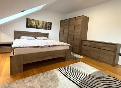 a bedroom with a bed and wooden cabinets and a rug at Log Garden Estate in Dobrova