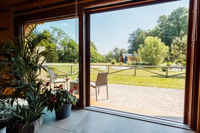 a sliding glass door with a chair on a patio at Log Garden Estate in Dobrova