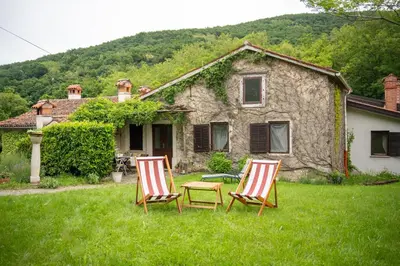 two chairs sitting in the grass in front of a house at Rustic House in Vipava Valley