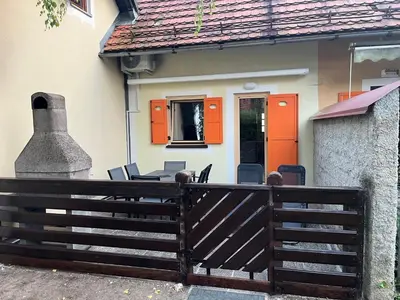 a house with an orange door and a table and chairs at APARTMA BUQEZ-HOUSE 79 with Termal Riviera Čatež tickets in Čatež ob Savi