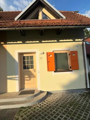 a small white house with an orange door at APARTMA BUQEZ-HOUSE 79 with Termal Riviera Čatež tickets in Čatež ob Savi