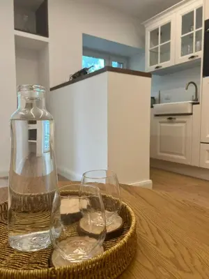 a table with two wine glasses and a bottle on it at Kolodvor 1870 - Old Town Apartment Kranj in Kranj