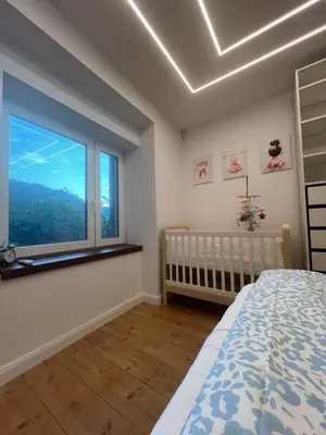 a bedroom with a crib and a large window at Kolodvor 1870 - Old Town Apartment Kranj in Kranj