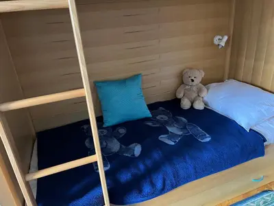 a teddy bear sitting on the bottom bunk of a bunk bed at Apartma Bučko in Bohinj