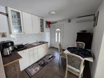 a kitchen with white cabinets and a table and a refrigerator at Pri tetki in Kranj