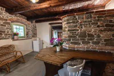 a room with a stone wall with a wooden table and chairs at House Dorče in Kojsko