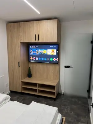 a bedroom with a television in a wooden cabinet at Private SPA with jacuzi, sauna & EV charging in Kranj