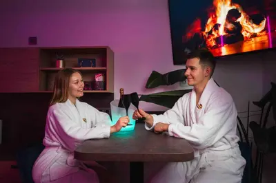 a man and woman sitting at a table with a drink at Private SPA with jacuzi, sauna & EV charging in Kranj