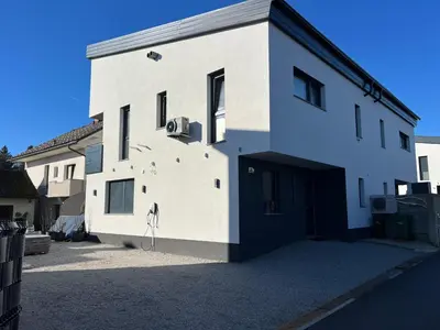 a white building with a door and a garage at Private SPA with jacuzi, sauna & EV charging in Kranj
