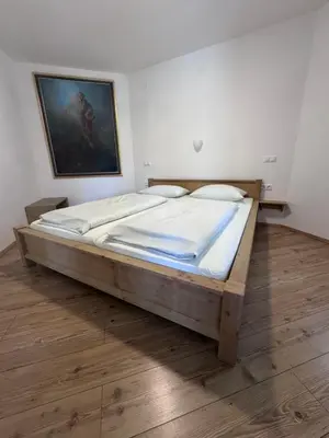 a large wooden bed in a room with a painting at Guesthouse Tolc in Spodnja Sorica