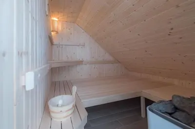 a wooden sauna with a bench and a bucket at Guesthouse Tolc in Spodnja Sorica