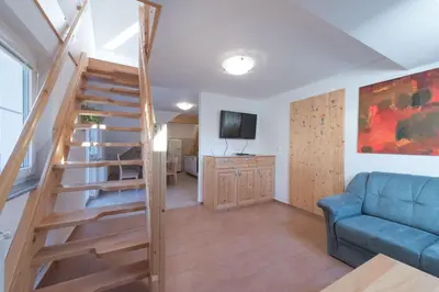 a living room with a staircase and a blue couch at Guesthouse Tolc in Spodnja Sorica