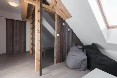 a room with a bed and a staircase with wooden walls at Guesthouse Tolc in Spodnja Sorica