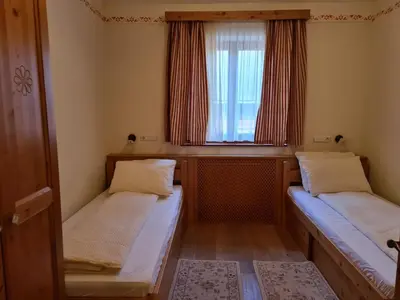 two beds in a small room with a window at Apartmaji Sitar in Ribnica na Pohorju