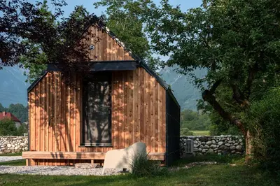 a wooden shed with a white chair in front of it at Telaj Residence - Cosy Cabins near Bovec, Soča Valley in Bovec