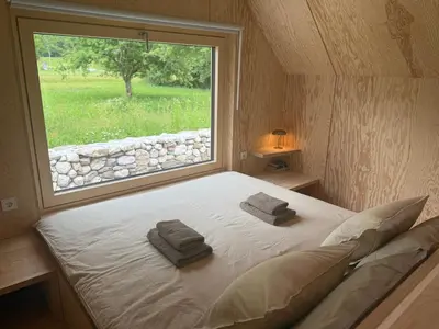 a bedroom with a large window with towels on a bed at Telaj Residence - Cosy Cabins near Bovec, Soča Valley in Bovec