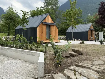 two wooden buildings in a yard with a garden at Telaj Residence - Cosy Cabins near Bovec, Soča Valley in Bovec